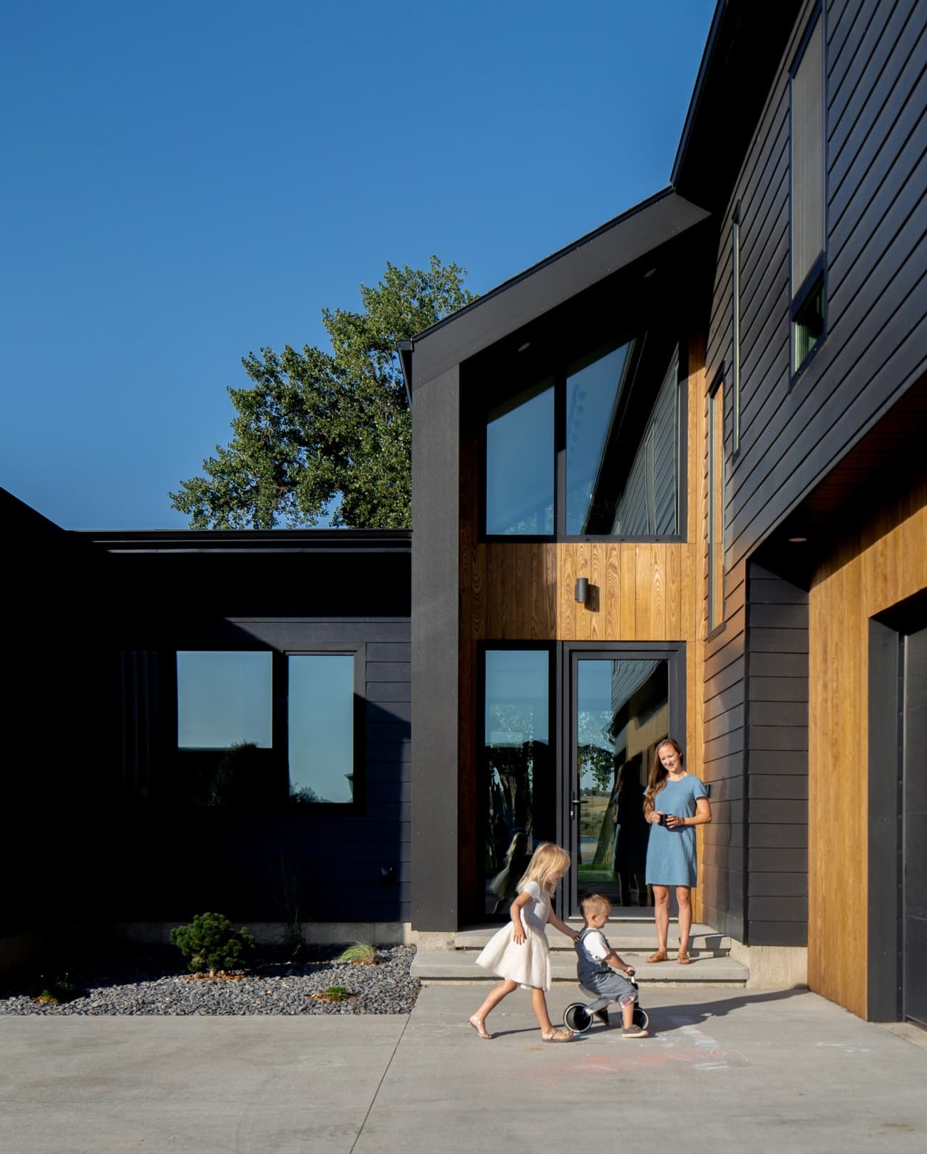 Mother with child in front of a modern house with wooden elements